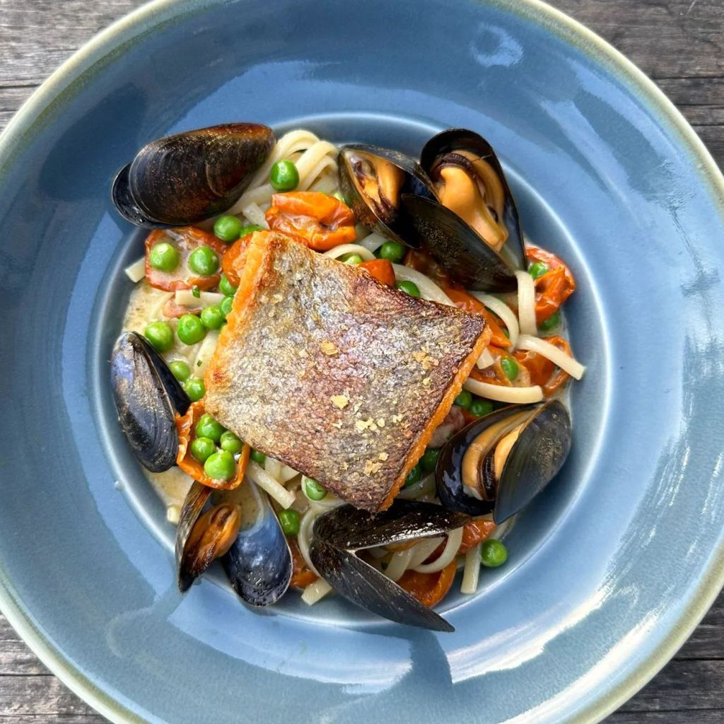 A piece of fish surrounded by clams in a creamy sauce, presented in a dish at the White Lion in Hebden Bridge. 