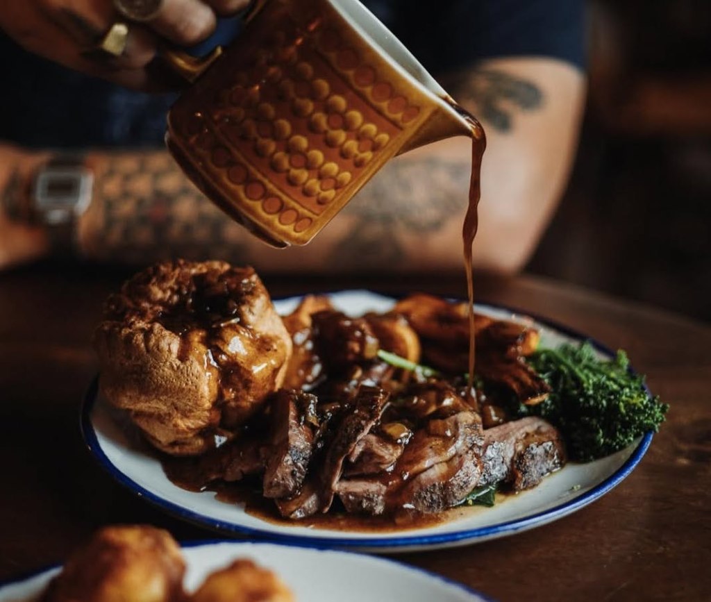 Someone pouring gravy over a Sunday roast at Hearth in Hull. 