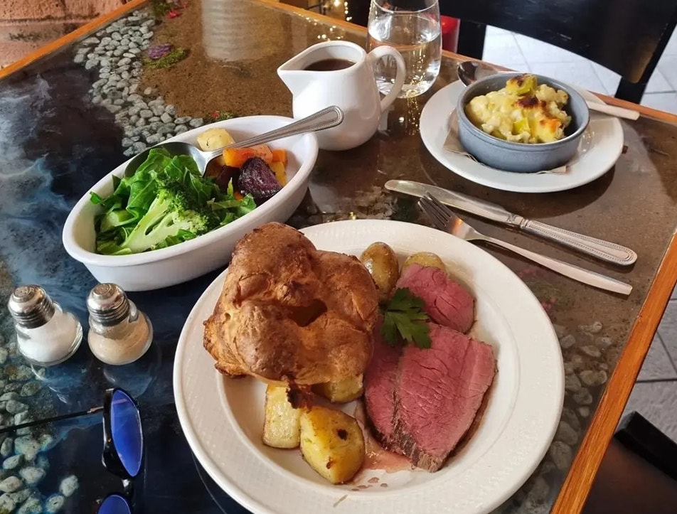 Sunday roast placed on a table with vegetables in side bowls. 