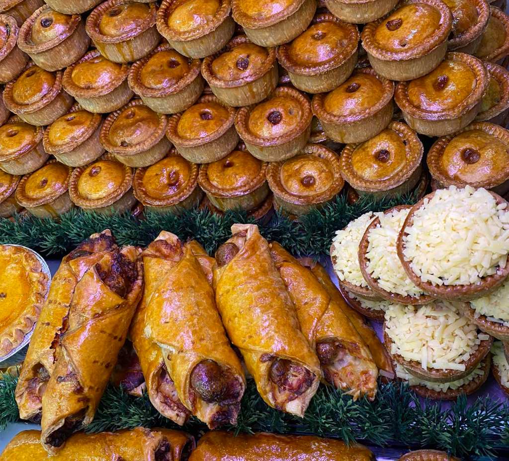A close up of the deli counter at Broster's Farm Shop in Yorkshire, with sausage rolls and pork pies presented in a case. 