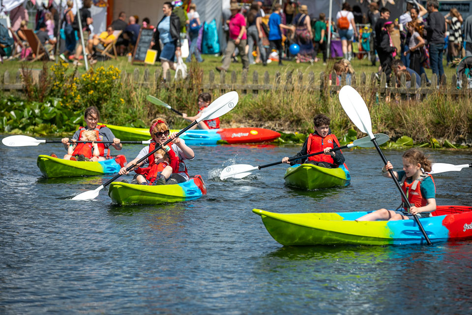 Multiple people kayaking in a lake in North Yorkshire at Deer Shed Festival. 
