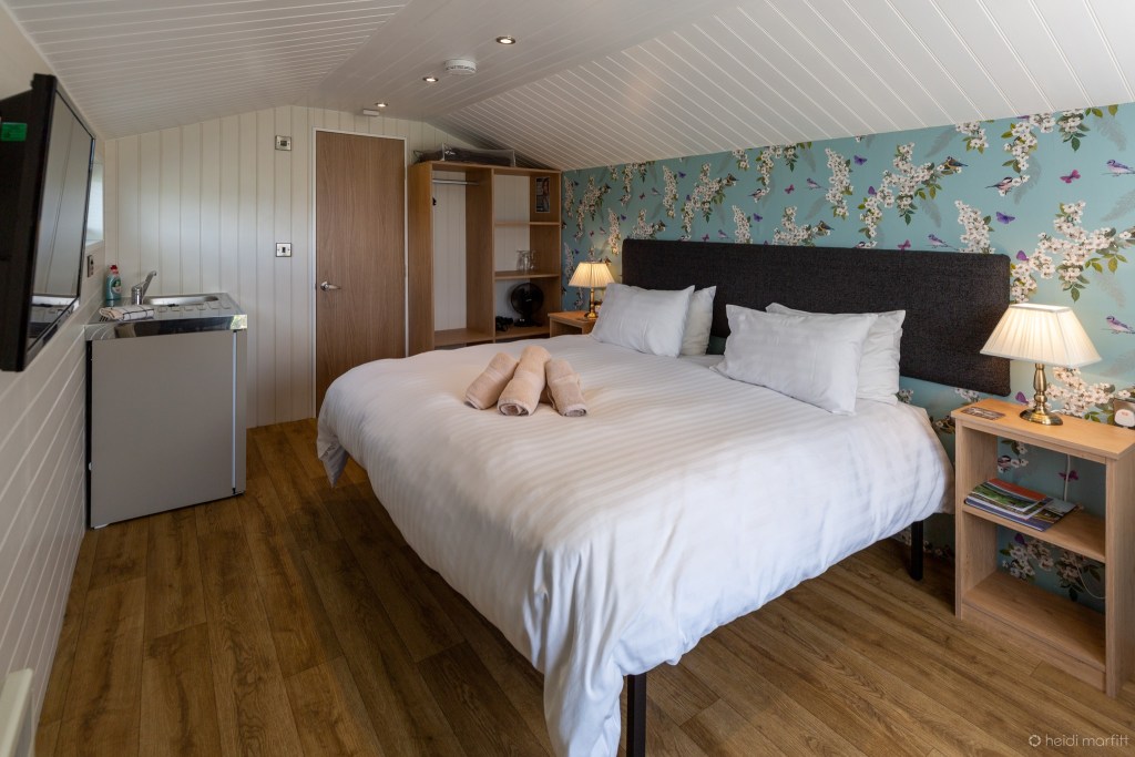 Inside a glamping pod at Wenningdale Escapes, with a double bed, tv and kitchenette in shot. 
