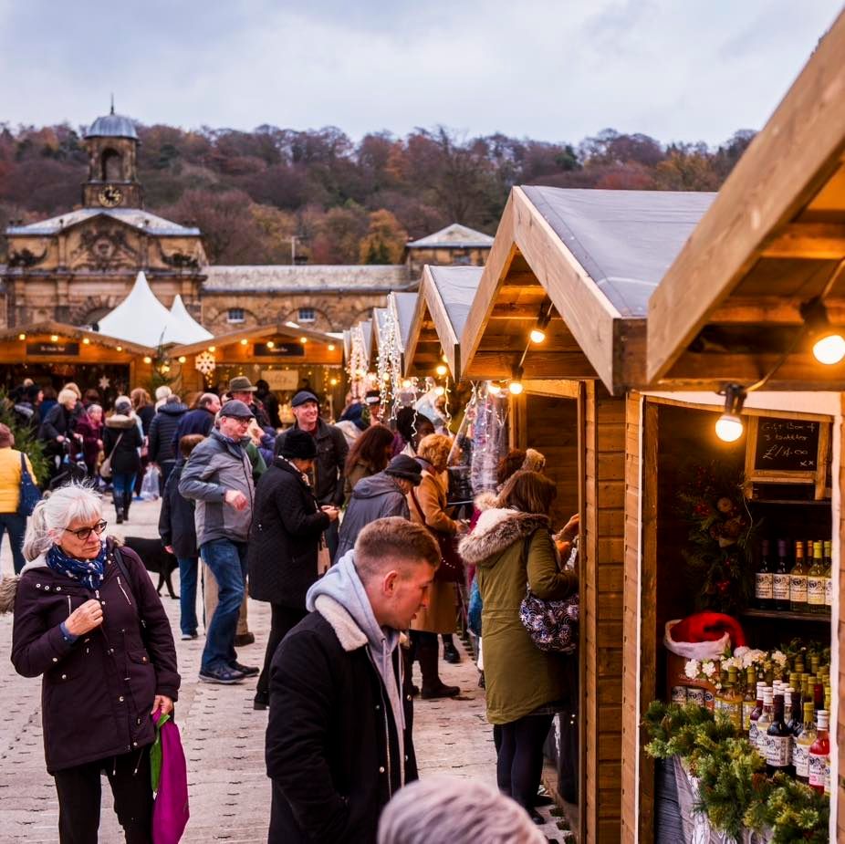 Christmas market stalls in the courtard at Chatsworth House, as shoppers peruse the stalls. 