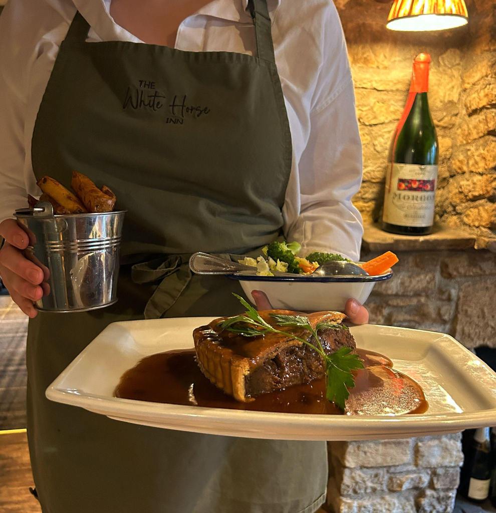 A pie served on a plate and held up by a waitress at The White Horse in Ampleforth. 