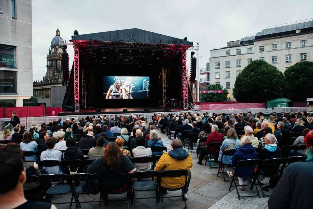 People watching a movie on a large screen outdoors in Leeds.