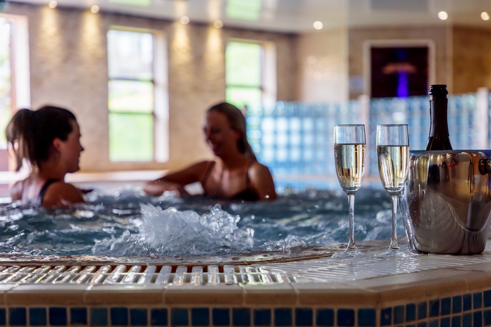 Two women chatting in a hot tub with prosecco at Long Ashes Park in Yorkshire.