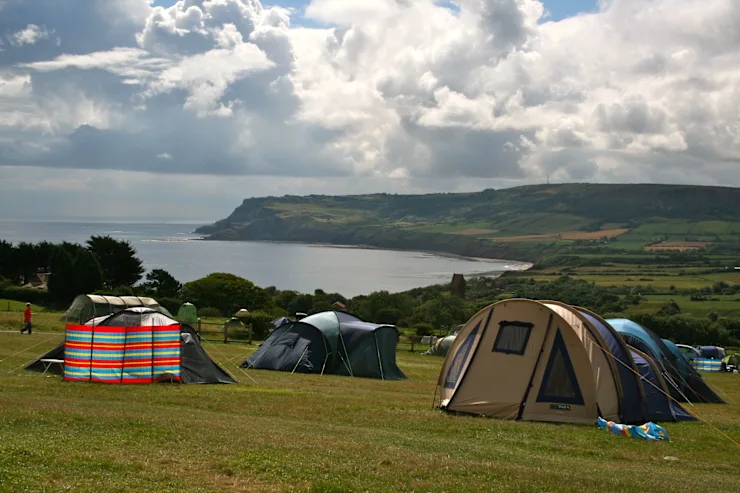 Tents pitched on a cliff overlooking the sea.