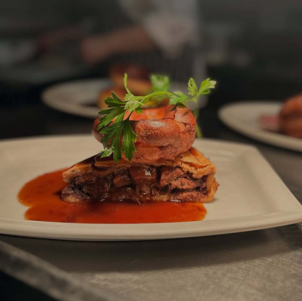 A slice of pie served with a Yorkshire pudding on top in the North York Moors. 